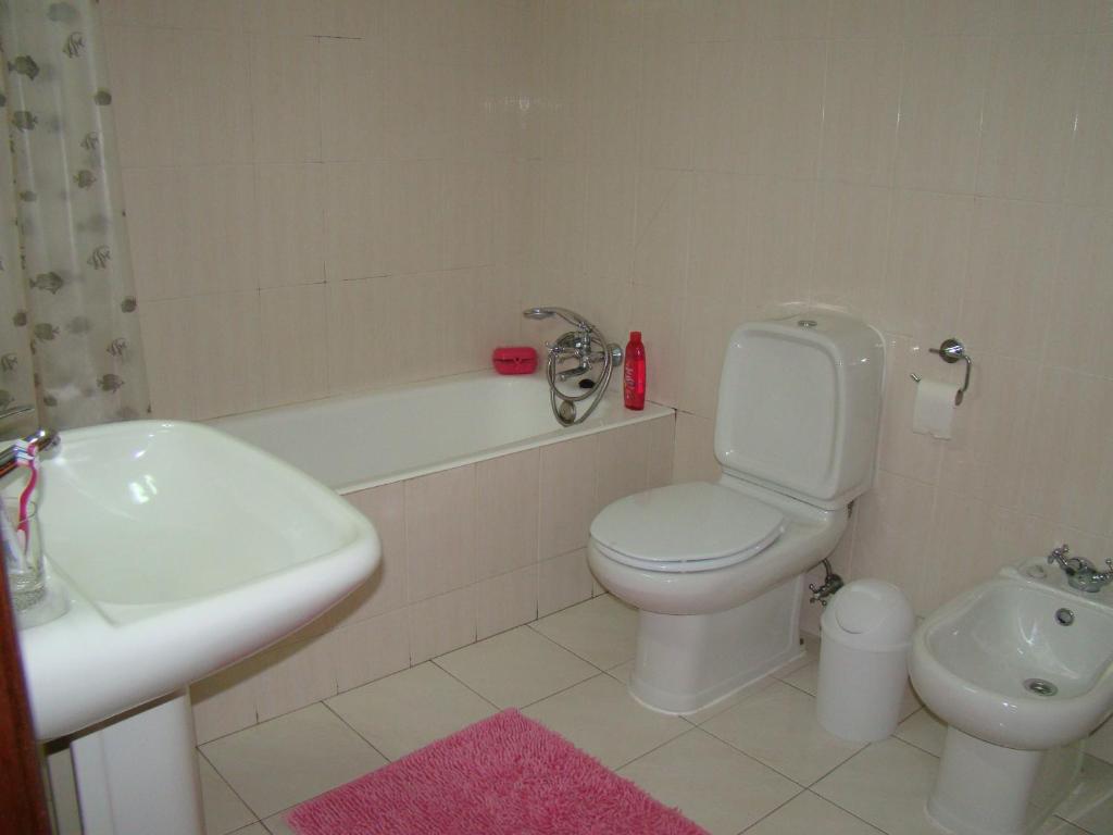 a bathroom with a toilet and a sink and a tub at GP Guest House in Alvor