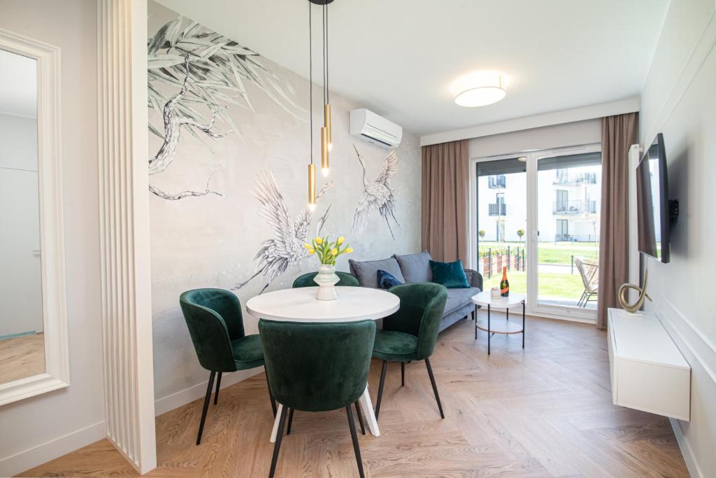 Una sala de estar con una mesa y sillas verdes. en Apartamenty Fale Morskie, en Jastrzębia Góra