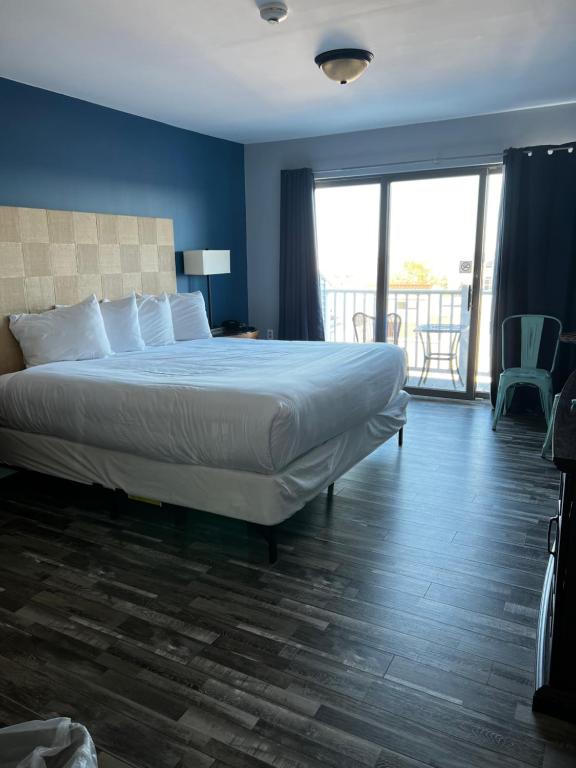 a bedroom with a large bed and a balcony at Trade Winds on the Bay in Rockland