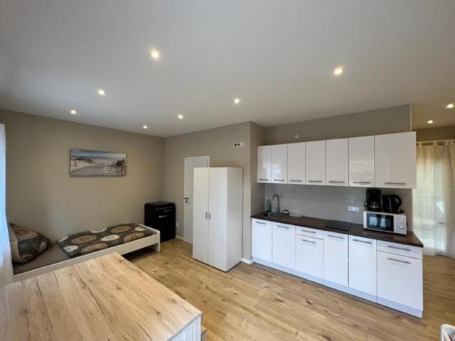 a kitchen with white cabinets and a couch in a room at Meridian Monteur Apartment in Rodenbach