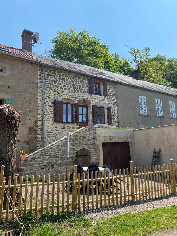 an old stone house with a wooden fence at Petit cocon au cœur du Morvan in Montreuillon