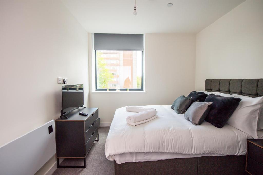 um quarto com uma cama com uma cómoda e uma janela em Gorgeous Old Trafford apartment em Manchester