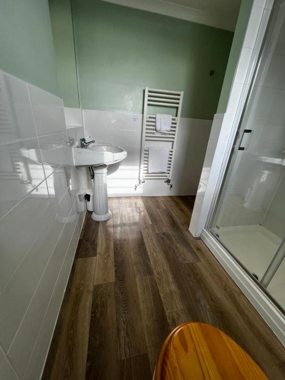 a bathroom with a sink and a glass shower at Queenswood Hotel in Weston-super-Mare
