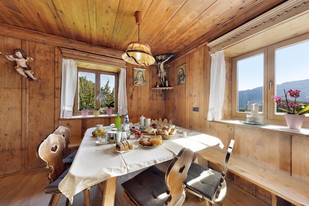 een eetkamer met een tafel, stoelen en ramen bij Moar im Rumsein - Apt Etschblick in San Genesio Atesino