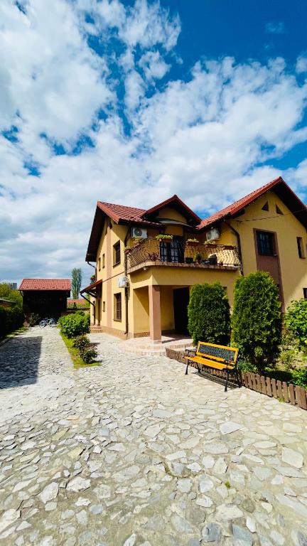 a yellow house with a bench in front of it at LETO House in Târgu Jiu