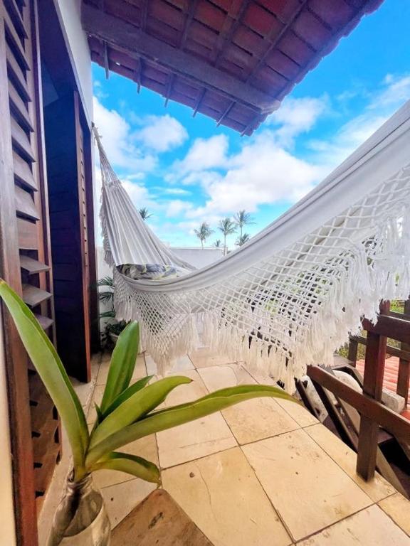 a hammock on a balcony with a palm tree at hospedagem da Mari in Jericoacoara