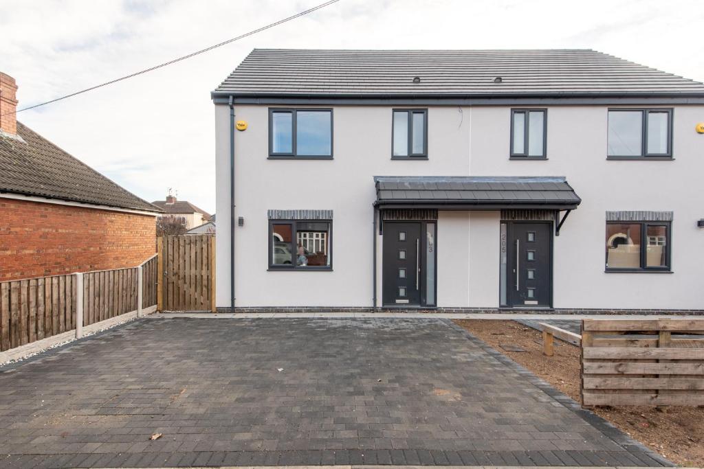 a white house with black doors and a driveway at No 205 in Doncaster