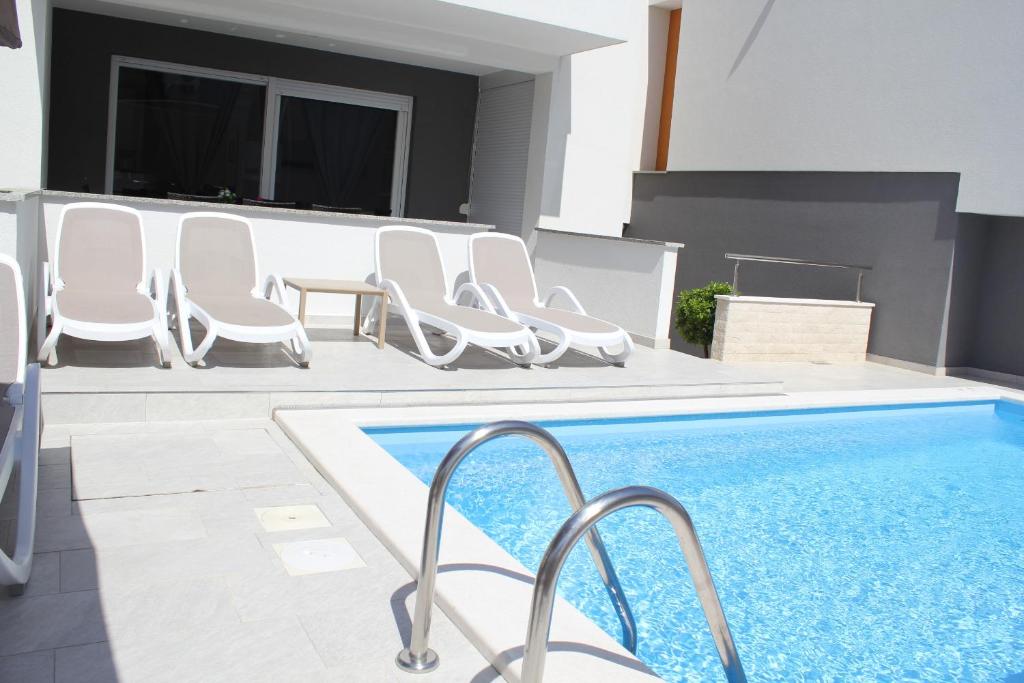 basen z białymi krzesłami i basen w obiekcie Apartment Villa Lumada with Pool w Novalji