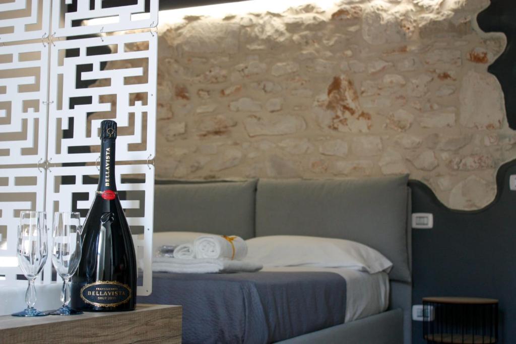 eine Flasche Wein auf einem Tisch neben einem Bett in der Unterkunft Muricis in Santeramo in Colle