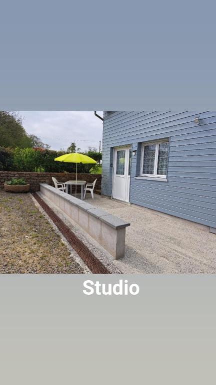 - une table de pique-nique avec un parasol jaune à côté d'un bâtiment dans l'établissement joli petit studio a la campagne, à La Trinité