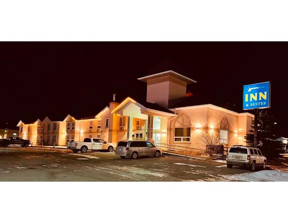 a inn with cars parked in a parking lot at night at Aurora Park Inn & Suites in Dawson Creek
