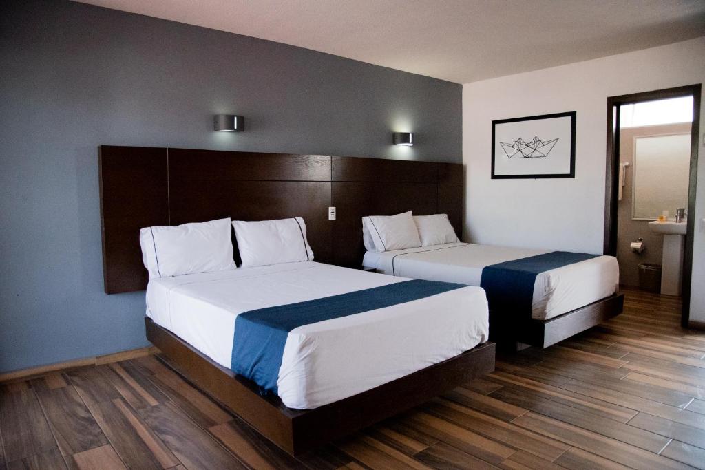 a hotel room with two beds and a window at Hotel Expo Plaza Business and Family Guadalajara in Guadalajara