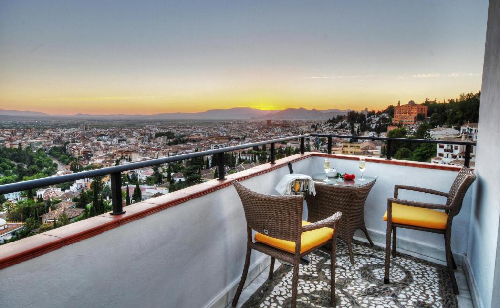 einen Balkon mit 2 Stühlen und einem Tisch mit Aussicht in der Unterkunft Hotel Mirador Arabeluj in Granada