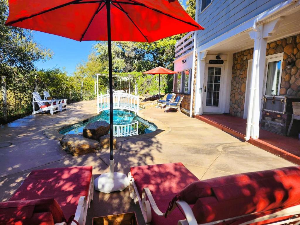 a patio with a red umbrella and chairs and a pool at Oak Hill Inn in Julian