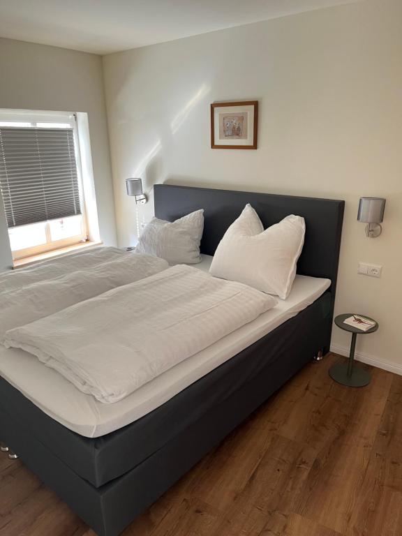 uma cama com lençóis brancos e almofadas num quarto em Im Zentrum, praktisch und ruhig em Greifswald