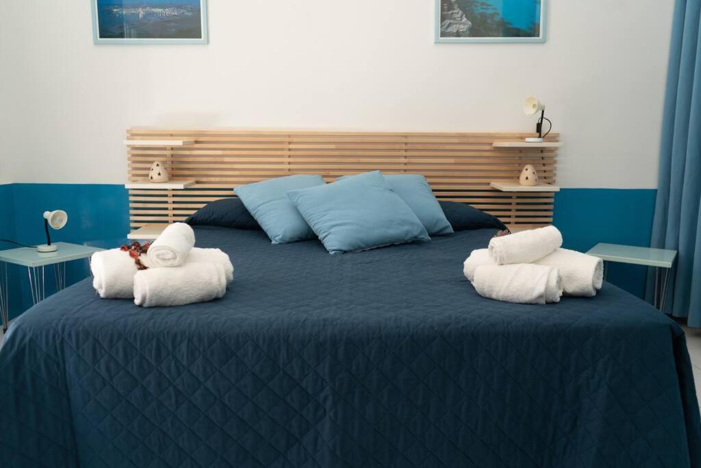 un grande letto blu con sopra asciugamani di Gioiello a due passi dal CENTRO a Favignana