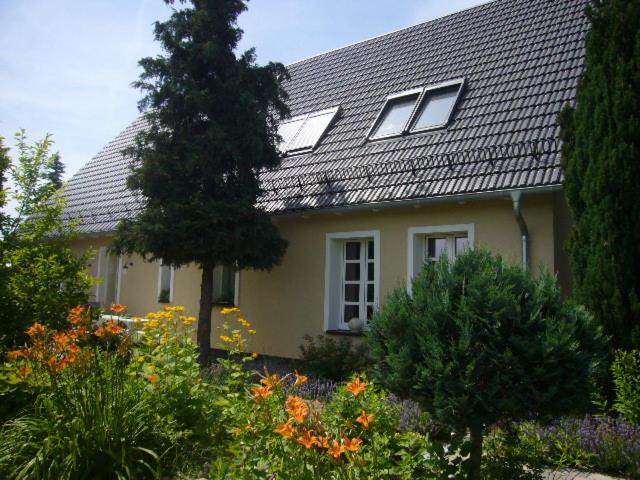 een geel huis met veel bloemen ervoor bij Ferienwohnung im Neubauernweg 3 in Hoppegarten