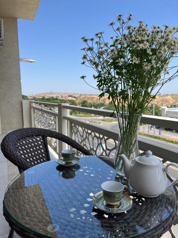 Samarkand luxury apartment #5 في سمرقند: طاولة مع إناء من الزهور وكوبين