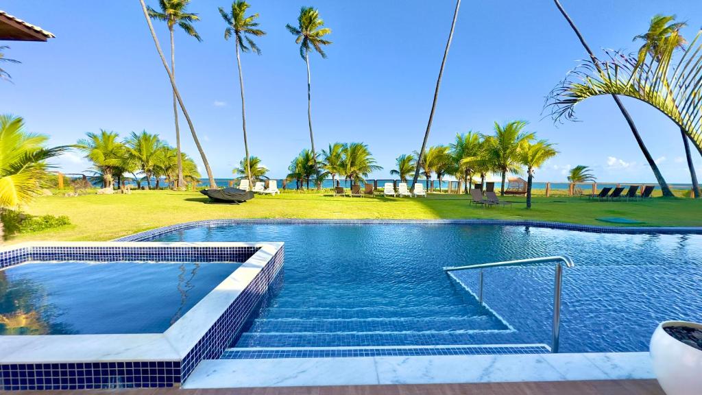 a swimming pool with palm trees in the background at Apto Novo beira-mar Praia de Itacimirim in Itacimirim