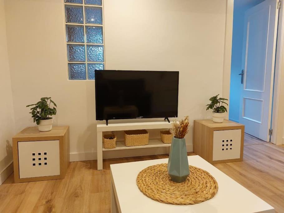 a living room with a flat screen tv and a table at Apartamento en Santander in Santander