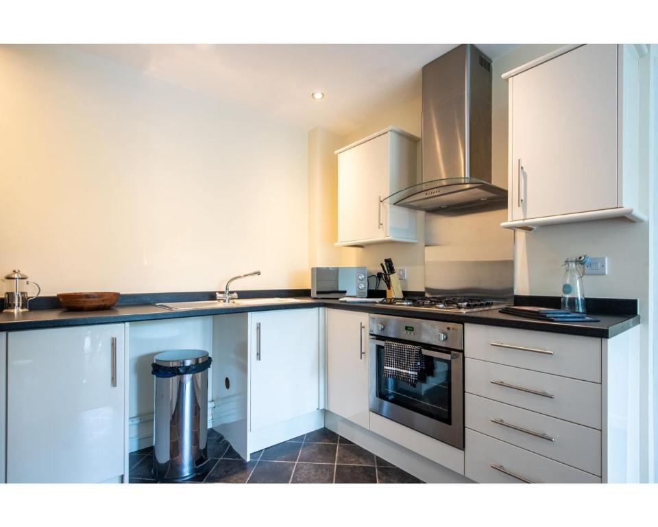 uma cozinha com armários brancos e um forno com placa de fogão em No7 em Mansfield