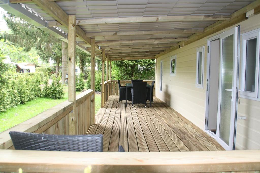 a deck with a pergola on a house at Chalet with large veranda 6p centrally located in National Park, Swimming pool in Wateren