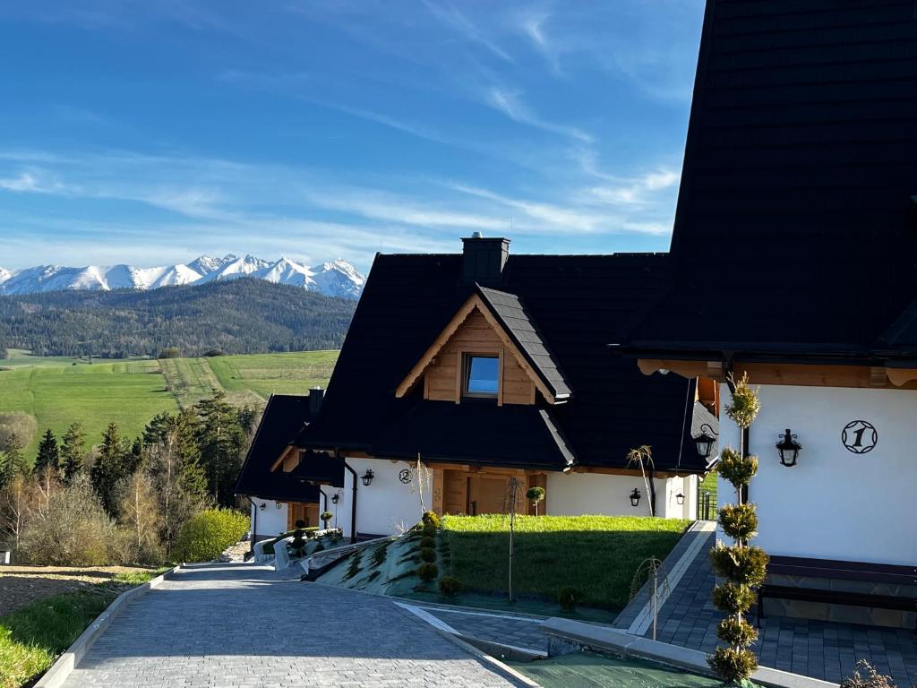 a house with a black roof with mountains in the background at Osada Wichrówka in Dursztyn