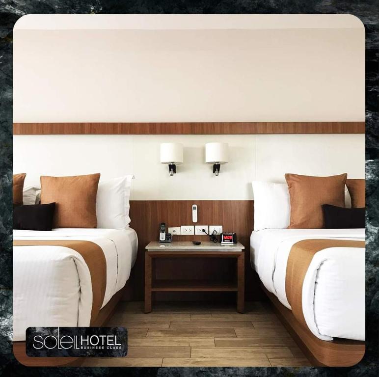 two beds in a room with a table between them at Hotel Soleil Business Class in León