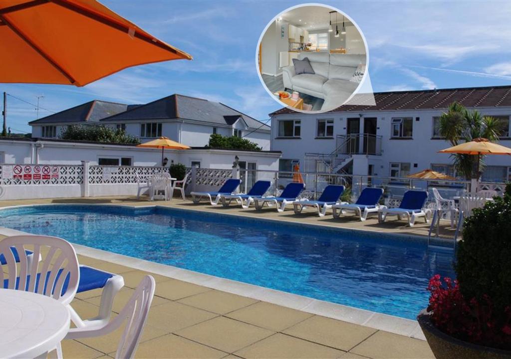 uma piscina com cadeiras, um guarda-sol e um espelho em Pool and Valley View em Mawgan Porth
