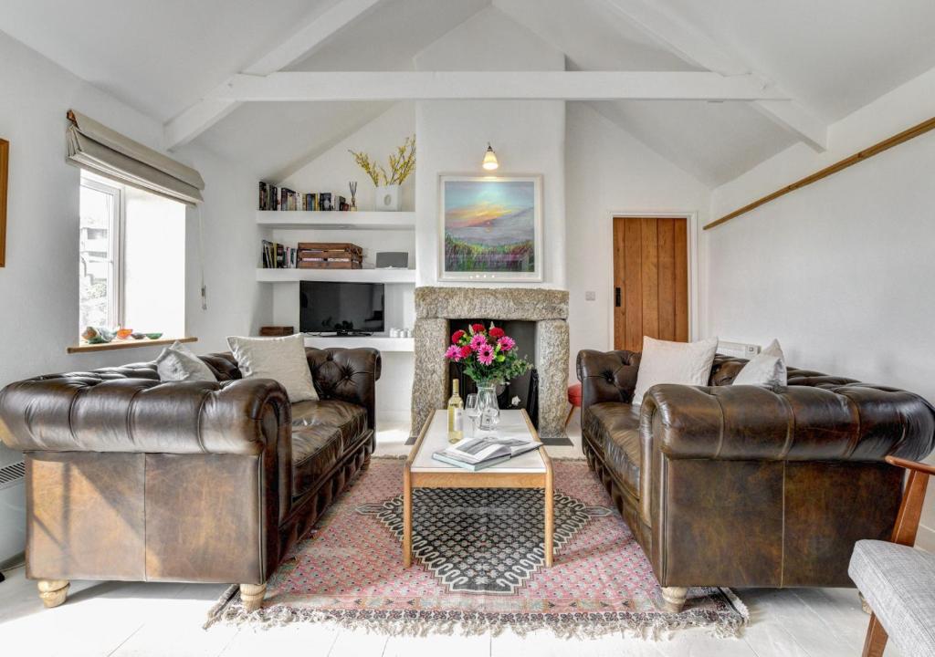 a living room with two leather couches and a fireplace at The Byre - Sennen in Sennen
