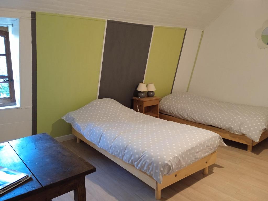 a small room with two beds and a table at Chambres d'hôtes de charme Le Pradel in Monceaux-sur-Dordogne