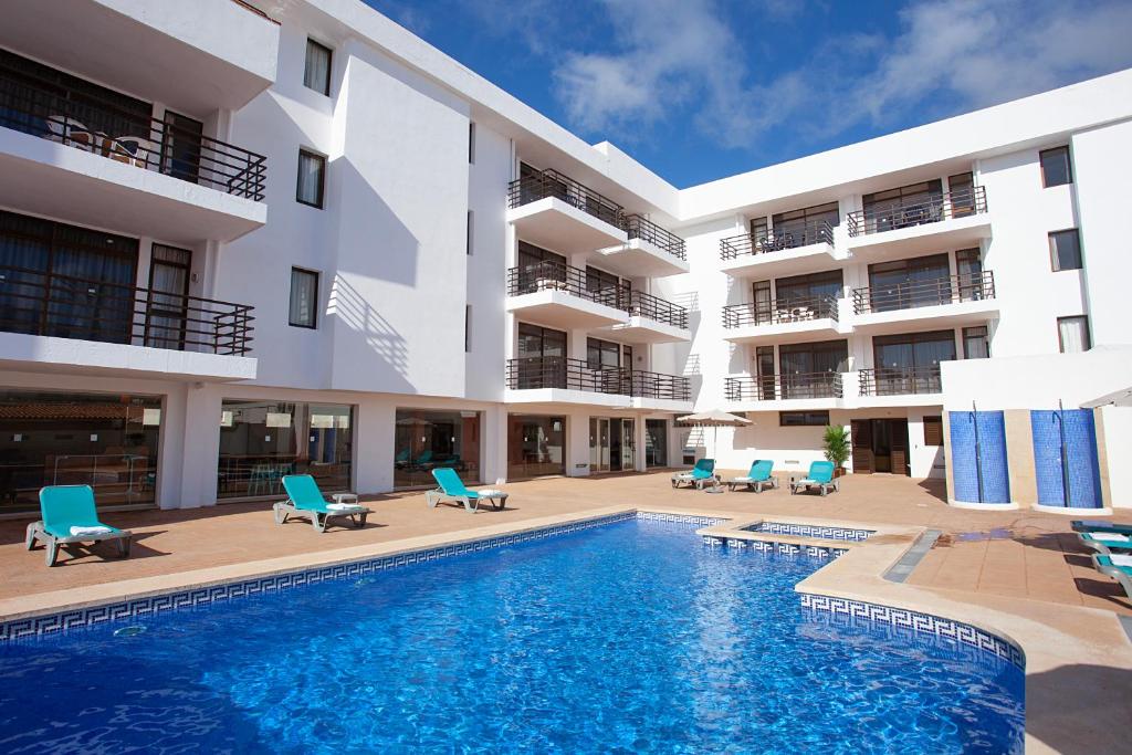 a swimming pool in front of a building at Apartamentos Don Quijote in Cala Ratjada