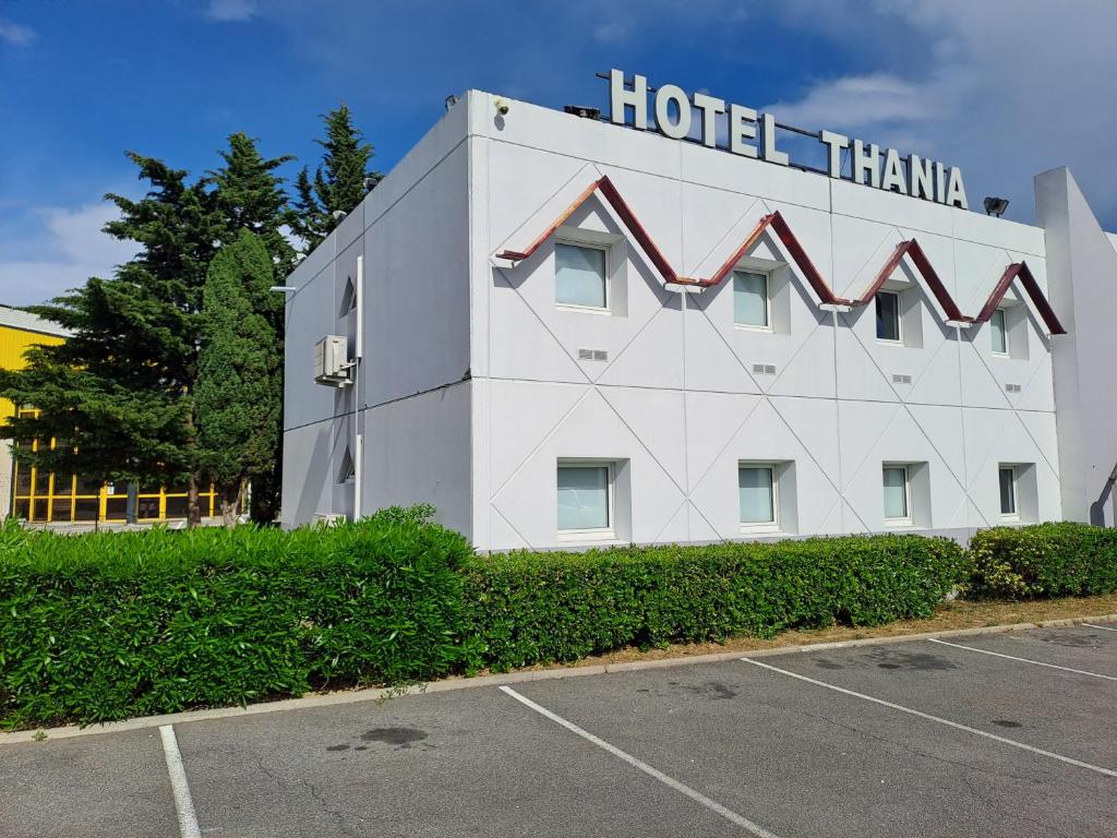ein weißes Hotel mit einem Schild darüber in der Unterkunft HOTEL THANIA in Frontignan
