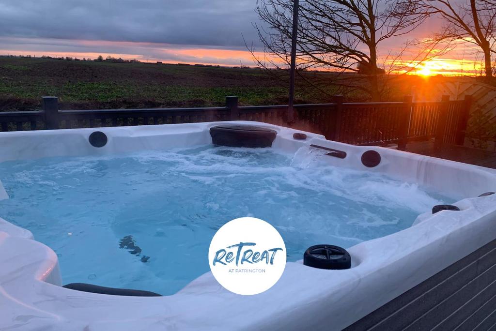 a jacuzzi tub with a sunset in the background at ReTreat Breaks - 47 Park Lane in Patrington