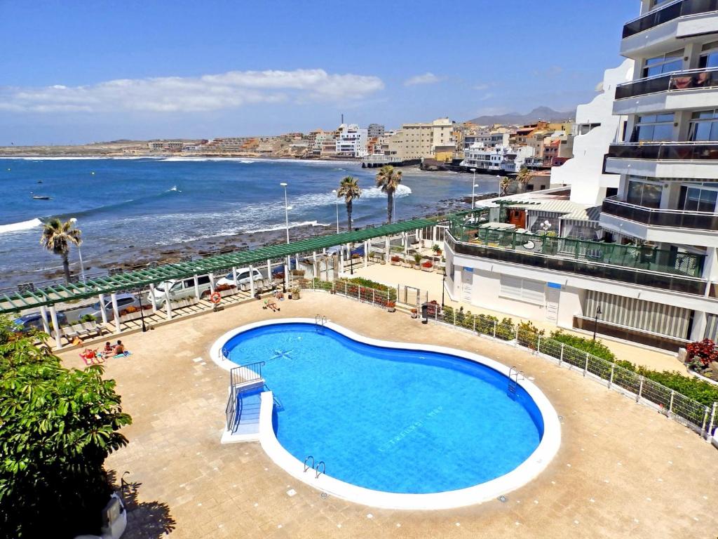 a swimming pool next to a beach and a building at Apartamentos Medano - Estrella del Mar in El Médano