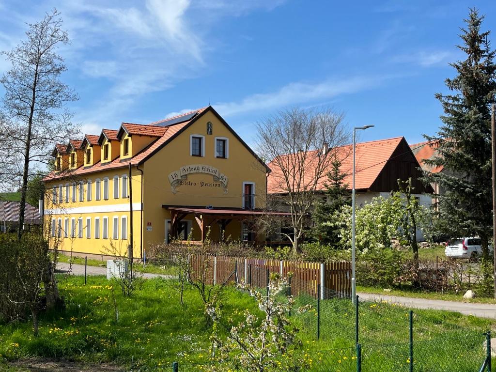 una casa amarilla con una valla delante de ella en Apart Pension Zelený grunt, 