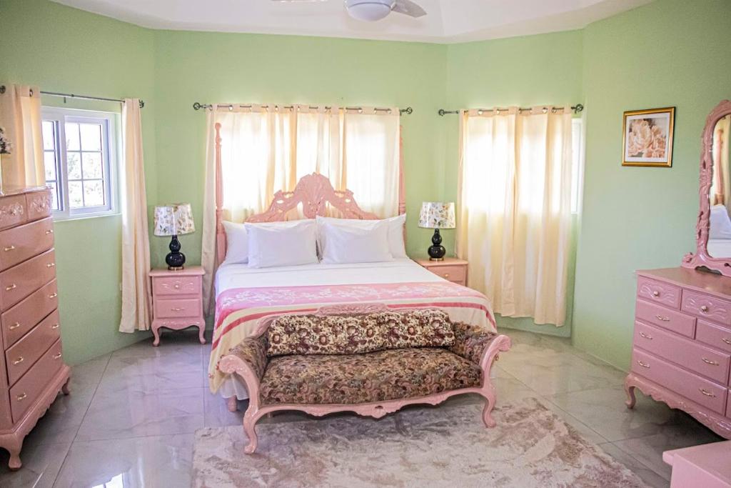 a bedroom with a large bed with pink furniture and green walls at The Hamilton's Nature Villa in Clarks Town
