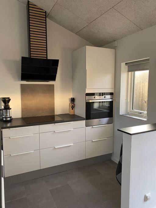 a kitchen with white cabinets and a stove top oven at Fin ny moderniseret lejlighed i Skagen. in Skagen