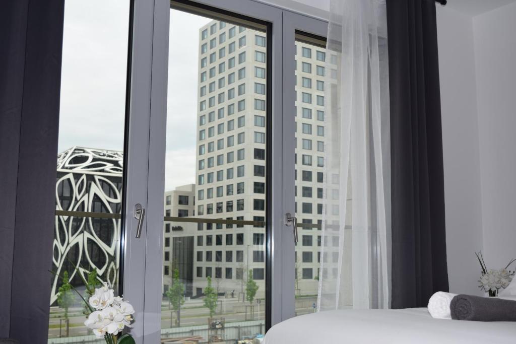 een slaapkamer met een raam met uitzicht op een hoog gebouw bij LAWSON'S GOLD BELL STUDIO in Luxemburg