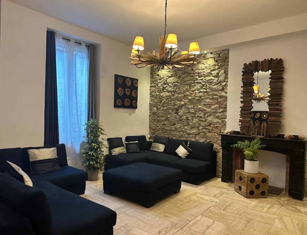 a living room with couches and a stone wall at La Maison du Puits in Cesseras