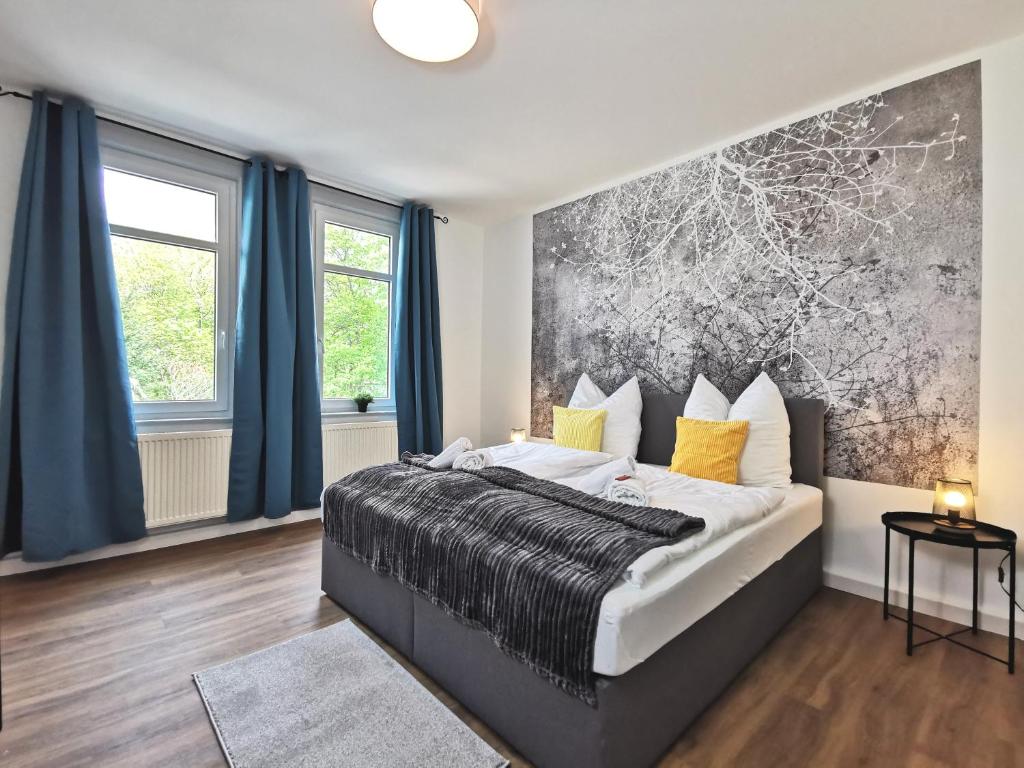 a bedroom with a large bed and blue curtains at BohnApartments Zechenhaus - Balkon - gratis Parkplatz - WLAN - sehr ruhig - barrierearm in Ilmenau