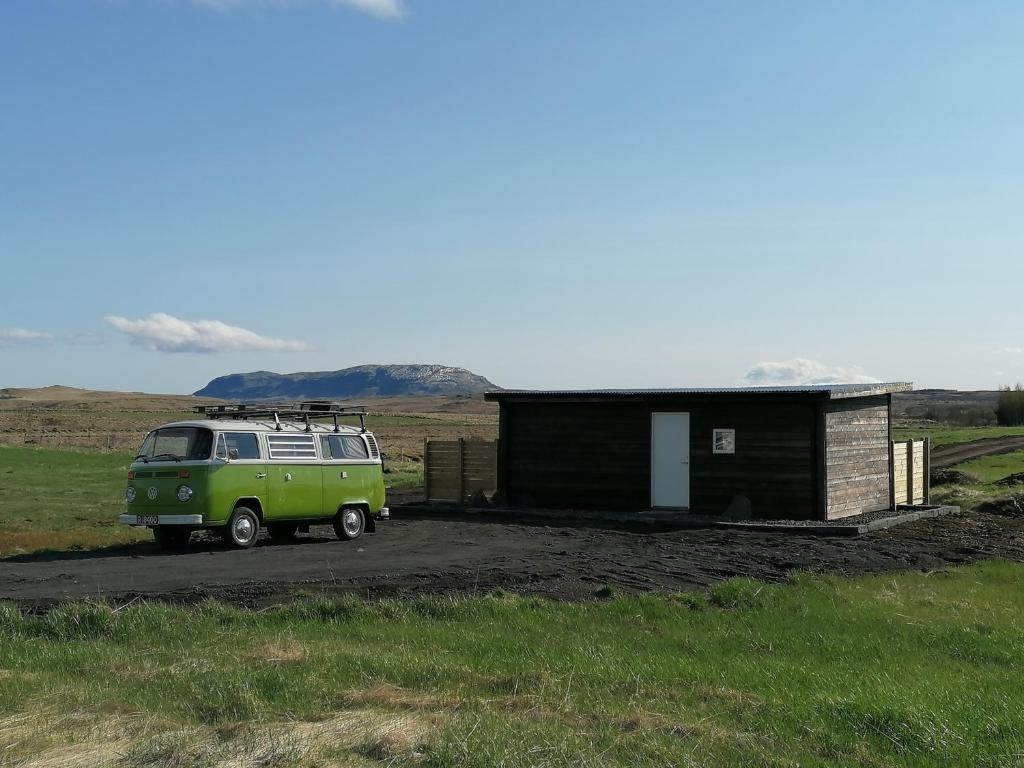 ein grüner Van neben einem kleinen Gebäude geparkt in der Unterkunft Blackwood cottage near Geysir in Reykholt