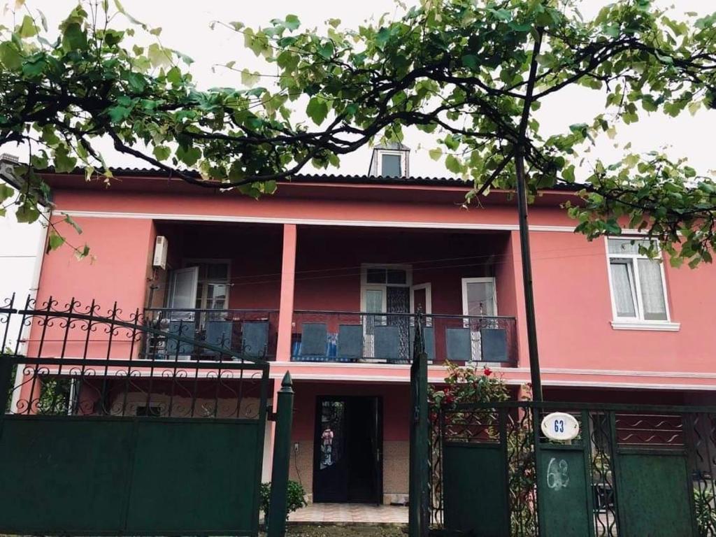 uma casa vermelha com uma varanda e uma cerca em Villa Lizzy em Batumi