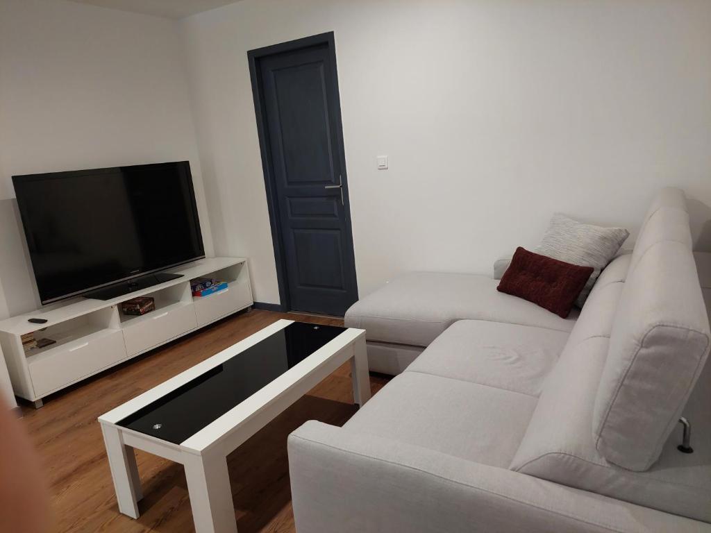 a living room with two white couches and a flat screen tv at bel appart T2 confortable en plein coeur de Sigean in Sigean
