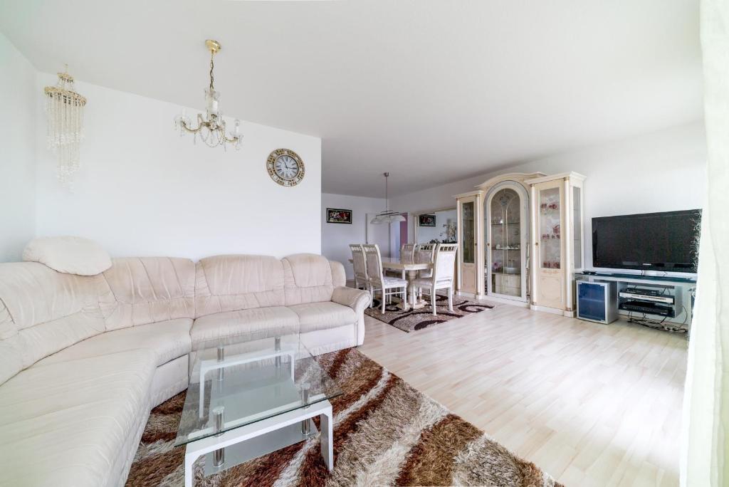 sala de estar con sofá blanco y TV en Private Apartment, en Hannover