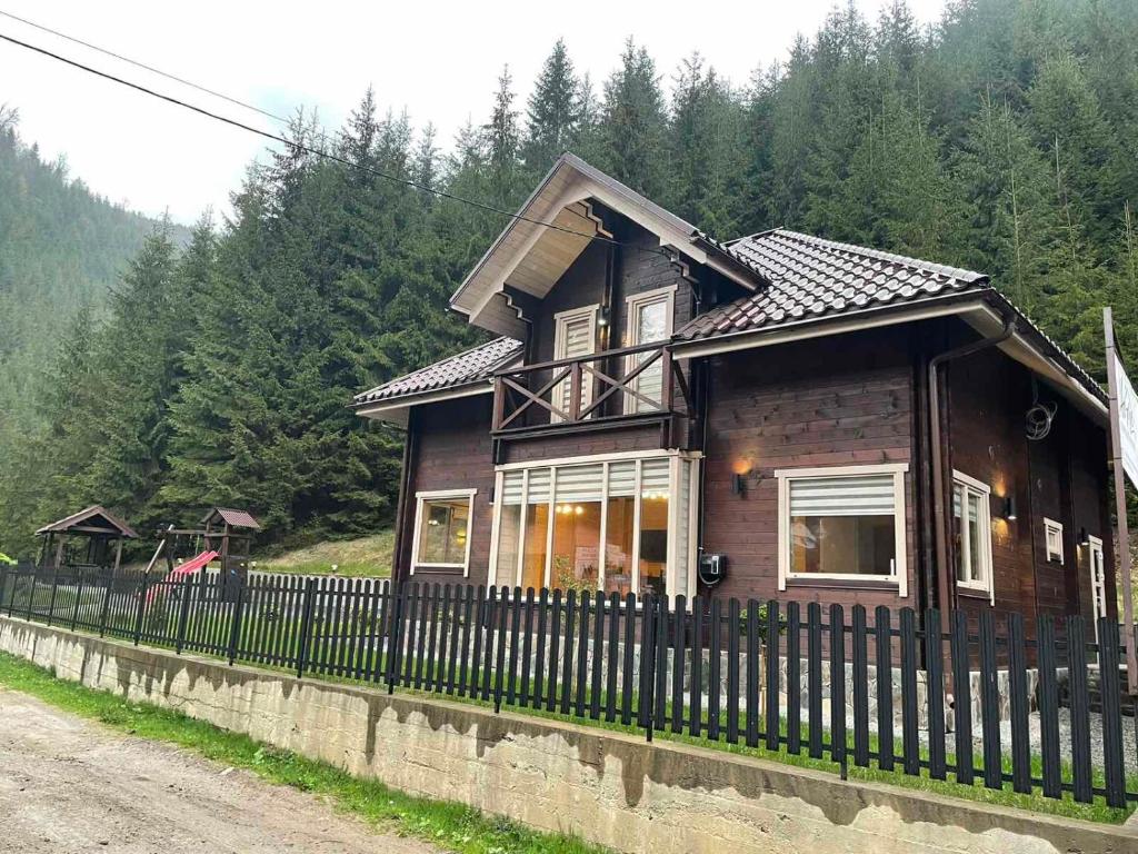 une petite maison en bois avec une clôture noire dans l'établissement Sweet Home, à Krasnyy