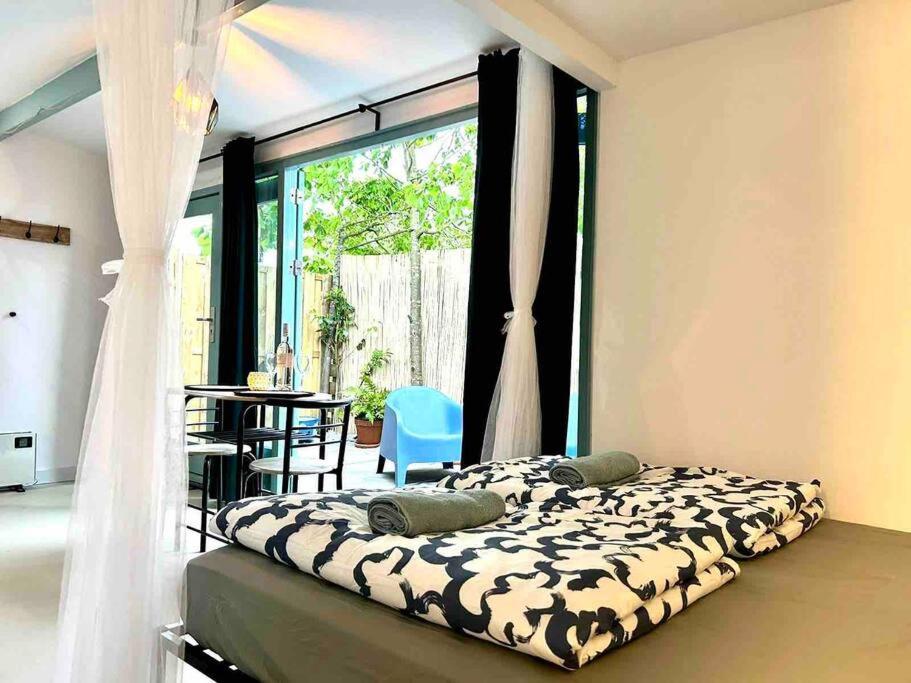 a bedroom with a bed and a large window at Cozy Ibiza style beach house with jacuzzi & private garden near Amsterdam in Vijfhuizen
