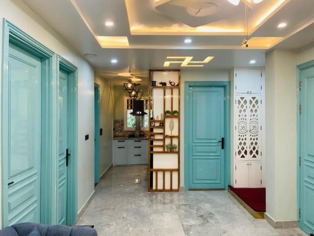 a hallway with turquoise doors and a kitchen at Urban Retreat in New Delhi