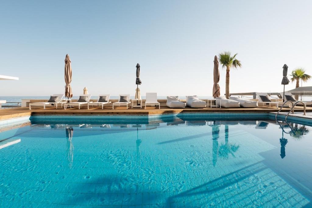 a swimming pool with lounge chairs and the ocean at Petradi Beach Lounge Hotel in Rethymno