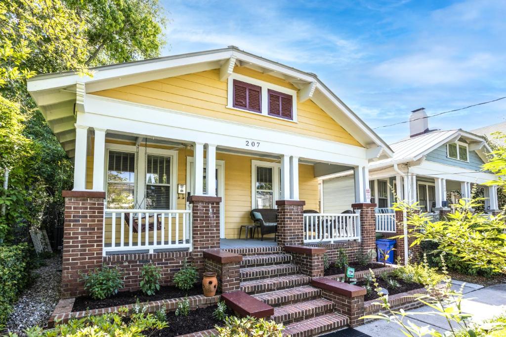 une maison jaune avec une terrasse couverte en briques et des escaliers dans l'établissement Historic District Delight, à Wilmington